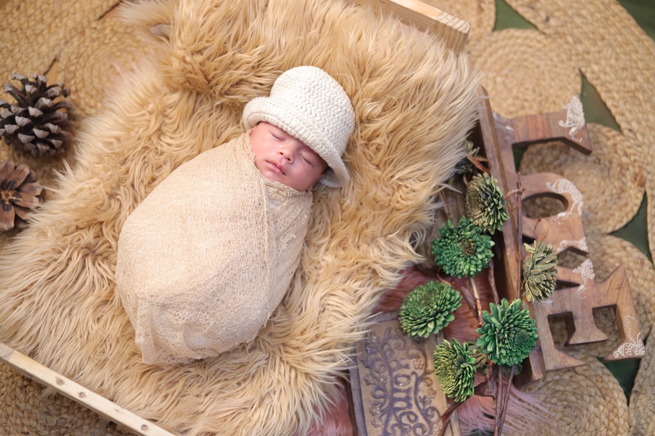 Newborn photoshoot — baby wrapped with 'LOVE' nameplate in studio